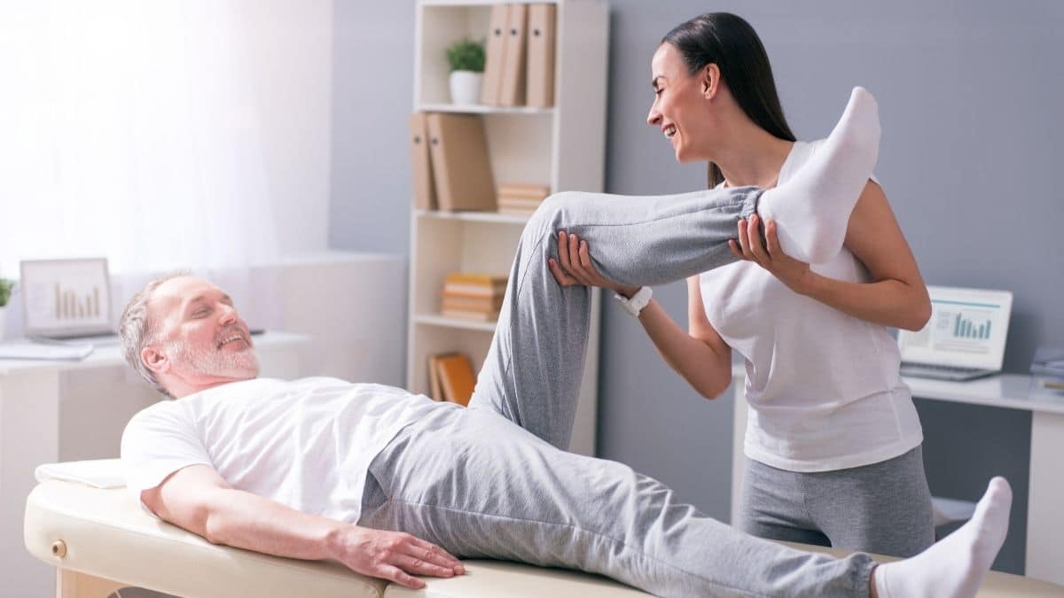 Fisioterapeuta ayudando a un adulto mayor con ejercicios de movilidad y equilibrio.